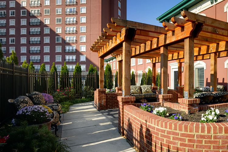A beautifully constructed pergola with brick pillars enhances the garden area of an urban residential complex.