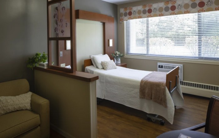 A clean and well-lit hospital room with a single bed and large window.