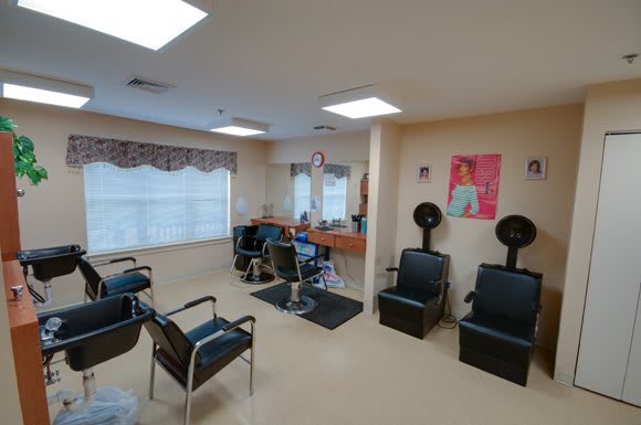 A well-lit hair salon equipped with chairs, mirrors, and hair dryers.