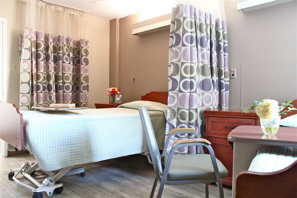 A neatly arranged hospital room with a bed, chair, and privacy curtains.