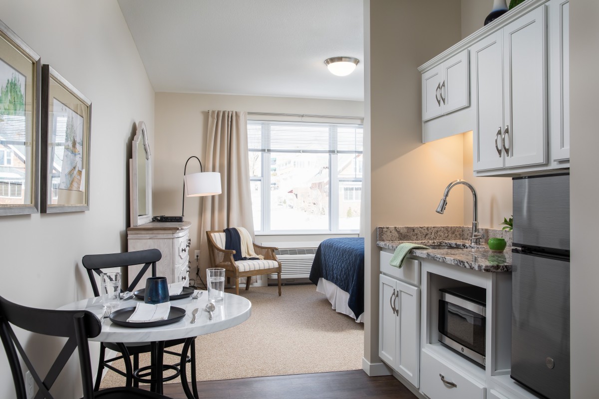 A cozy studio apartment featuring a compact kitchen and a comfortable living area.
