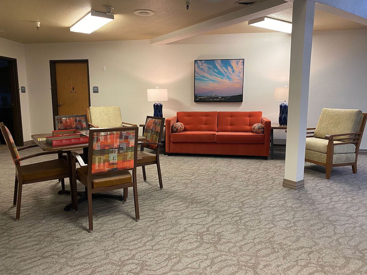 A cozy seating area with a red sofa, chairs, a table, and decorative lamps.