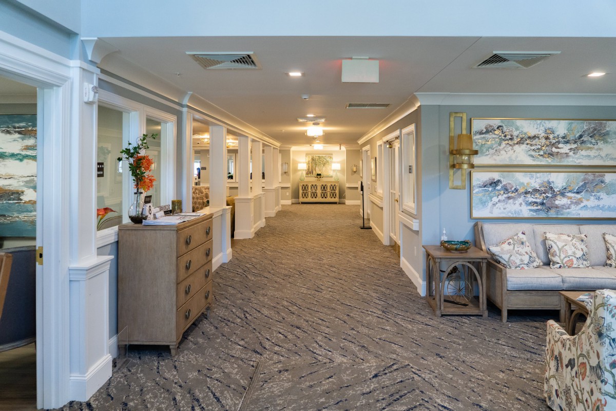A spacious, well-lit hallway featuring decorative furniture and artwork on the walls.