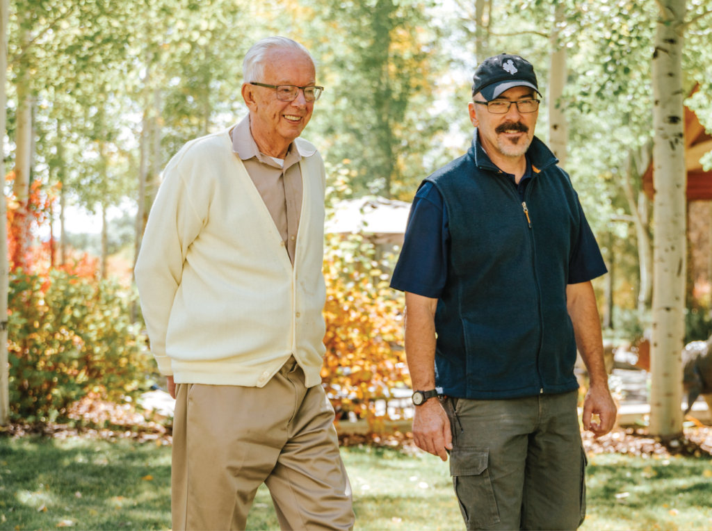 Two men walking together in a park-like setting.