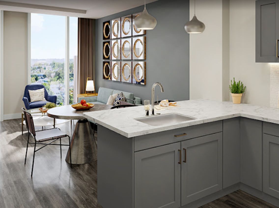 A modern kitchen with an island counter seamlessly connects to a cozy living room, showcasing a stylish open-concept design with ample natural light.