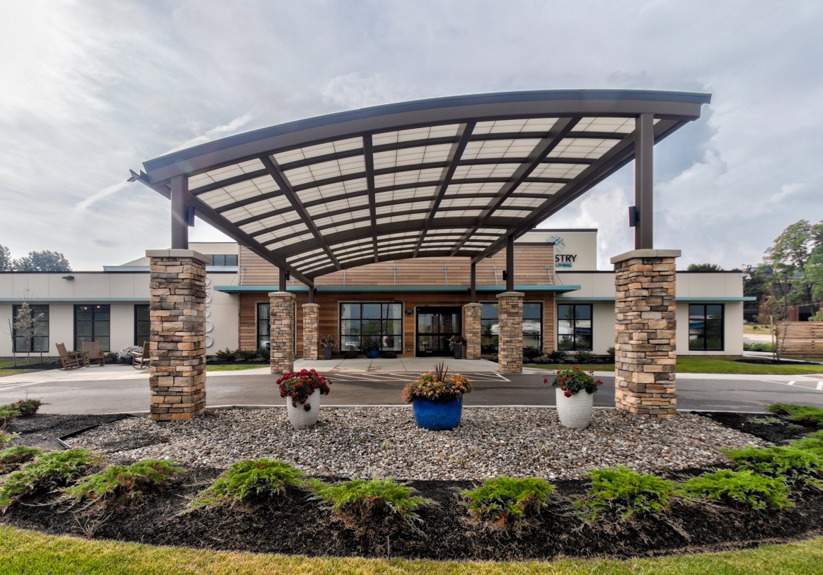 Modern building entrance with a stylish awning and landscaped surroundings.