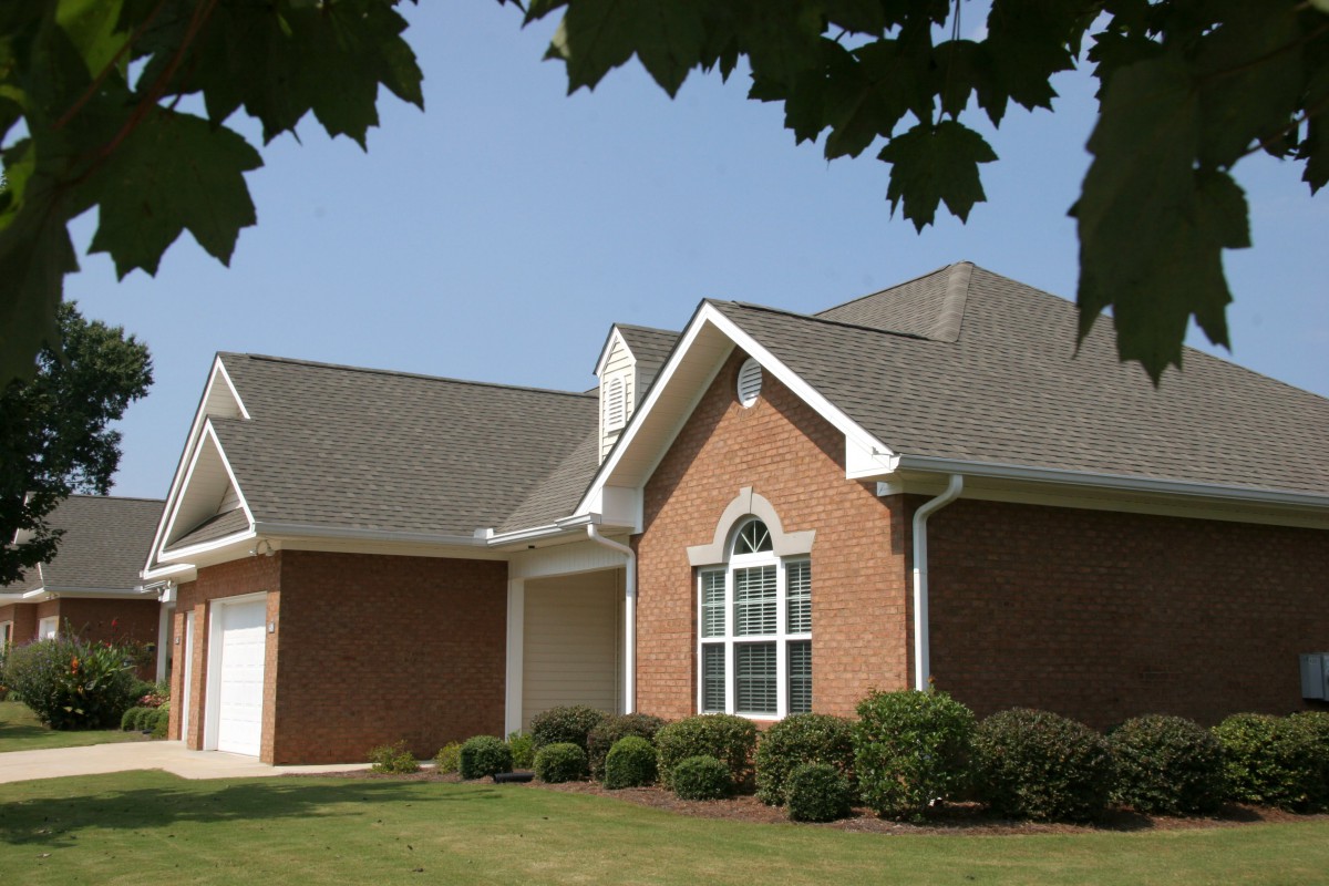 A suburban brick house with a well-kept lawn and attached garage.