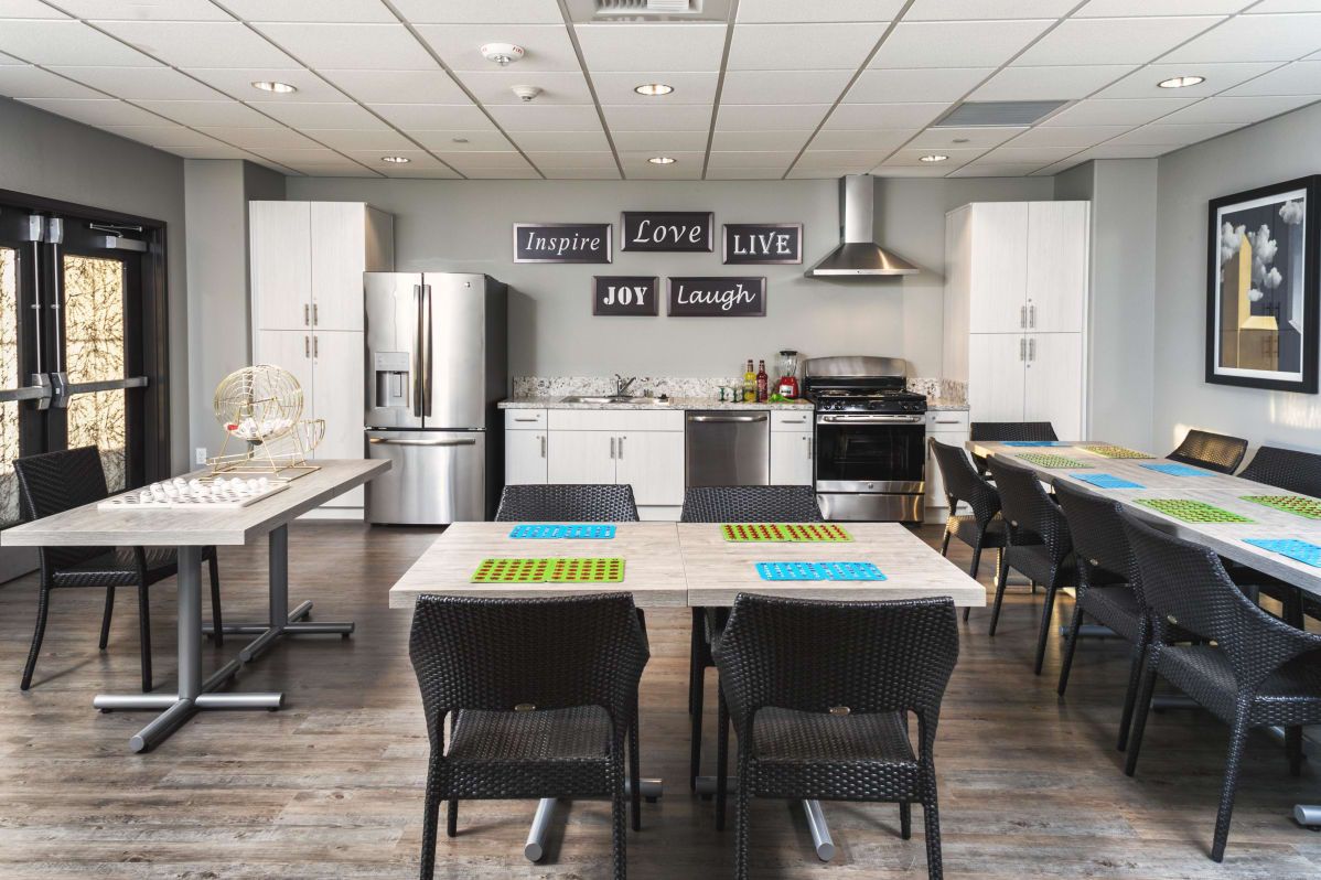 A modern kitchen and dining area featuring stainless steel appliances, stylish decor, and neatly arranged tables and chairs.