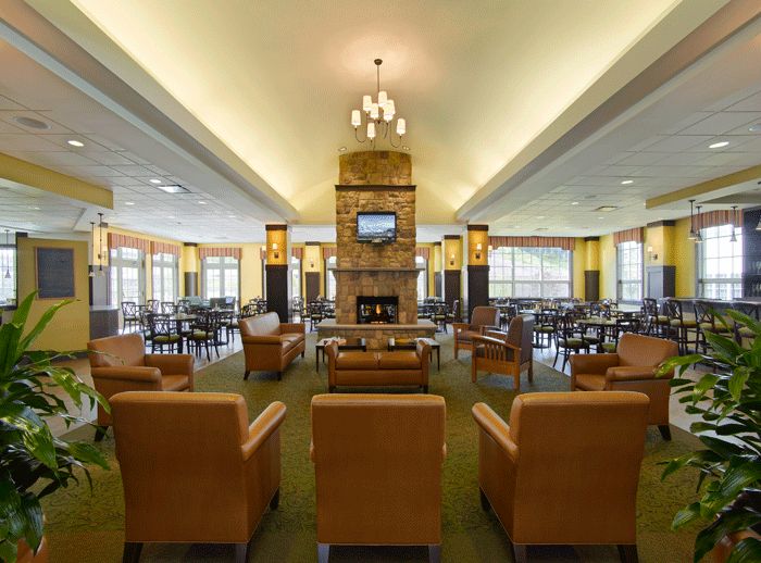 A spacious lounge area featuring comfortable seating, a central fireplace, and a mounted television.