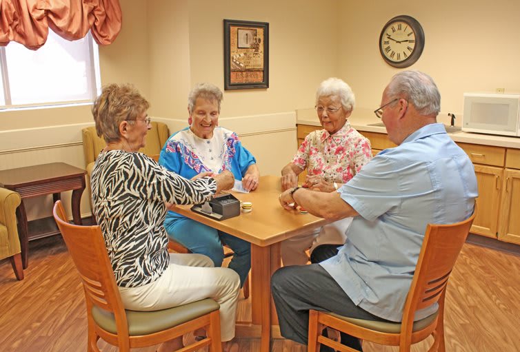 A group of seniors enjoying a card game at a table indoors.