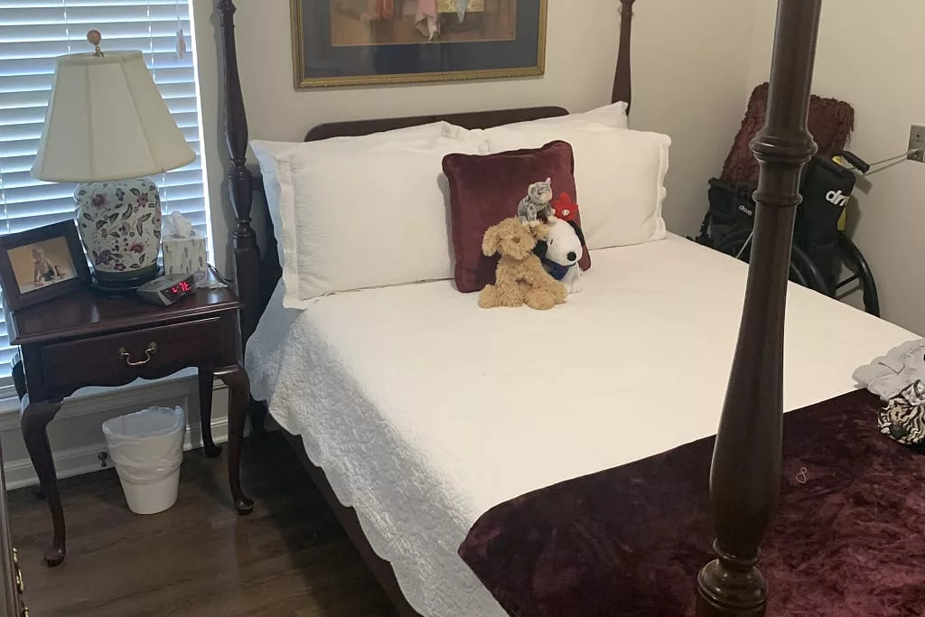 A neatly made bed with decorative pillows and stuffed animals in a cozy bedroom.