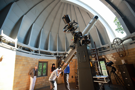 Visitors exploring the telescope inside an observatory.