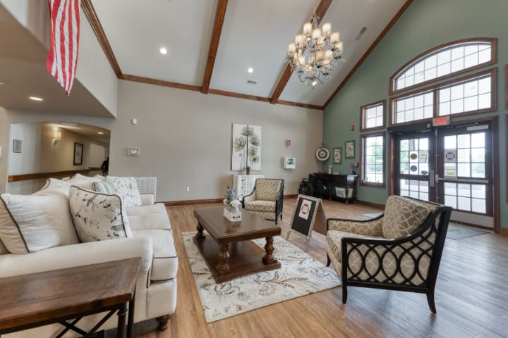 Spacious living room with elegant dcor, featuring a chandelier, high ceilings, and comfortable seating.