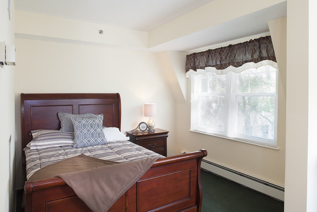 A cozy bedroom with a wooden bed frame, soft lighting, and a window adorned with curtains.