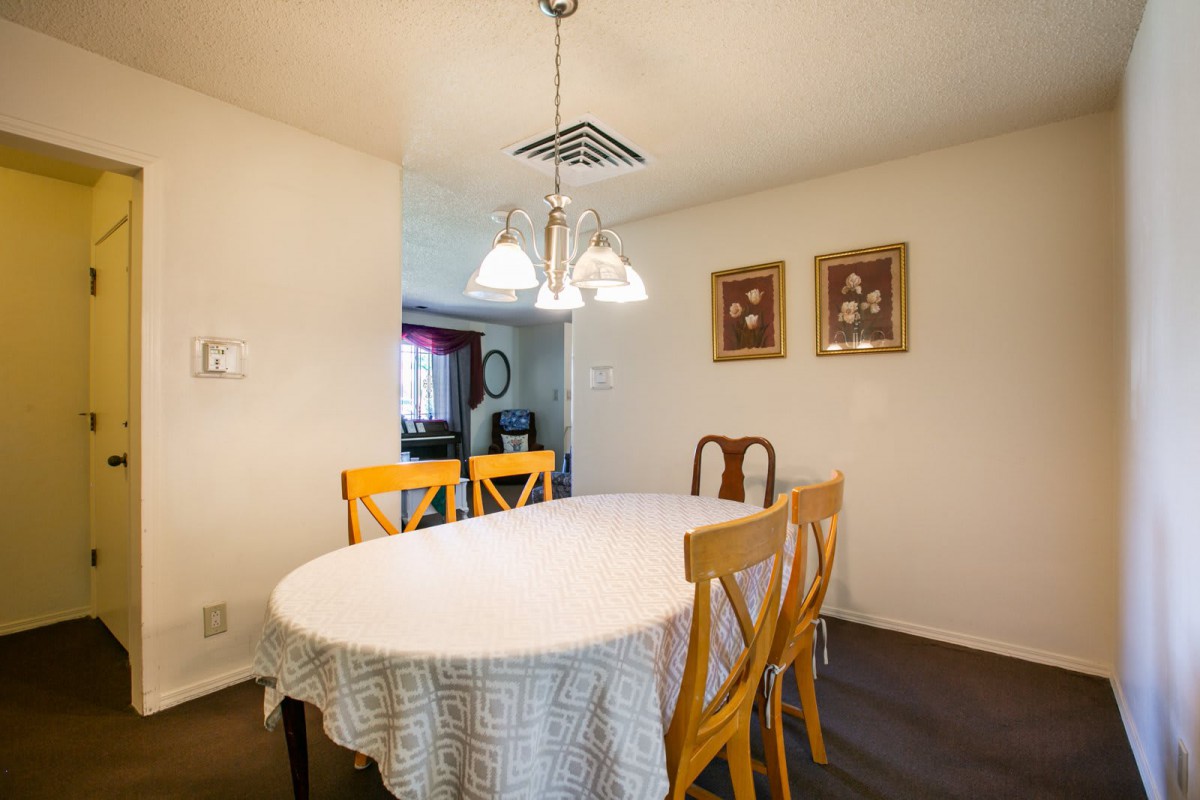 A cozy dining room with an oval table and mixed-style chairs under a hanging chandelier, adorned with framed artwork on the walls.