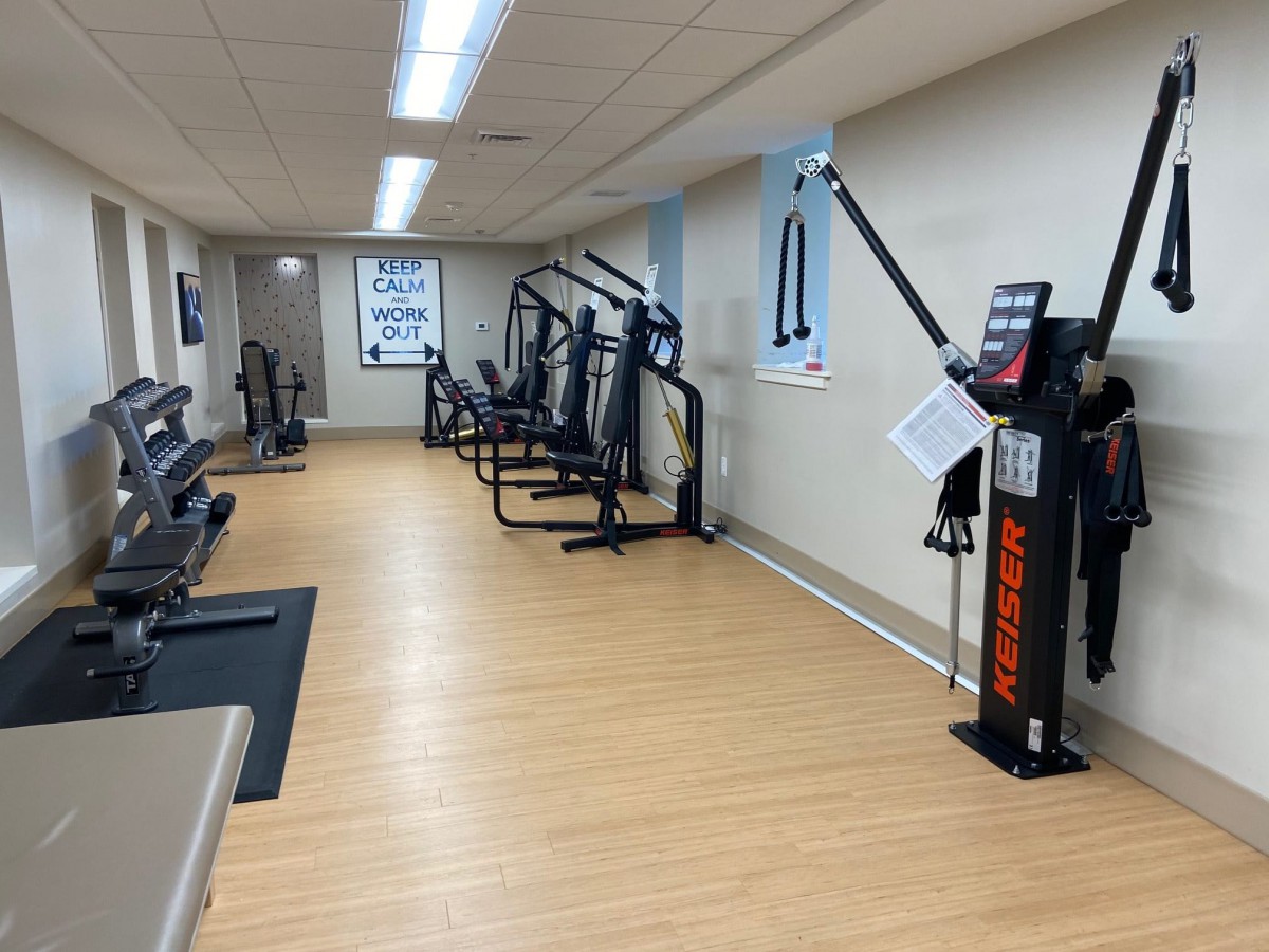 A well-equipped gym with various exercise machines lined up against the wall.