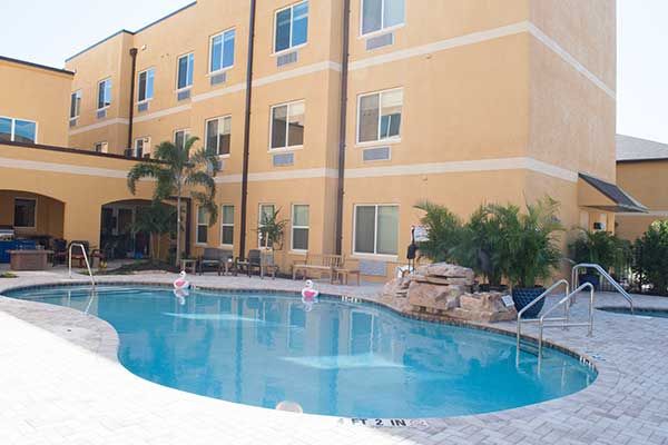 Outdoor swimming pool area at a hotel with surrounding palm trees.