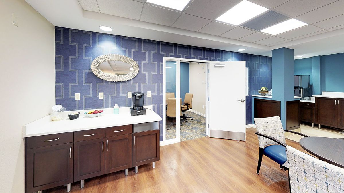 A modern office space featuring a conference room, coffee station, and stylish blue walls.