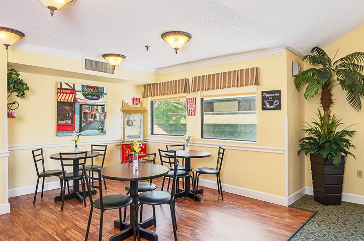 A cozy dining area with yellow walls and round tables arranged neatly.