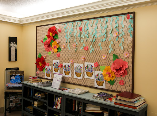 A vibrant bulletin board decorated with paper flowers and cheerful illustrations, perfect for showcasing creative projects.