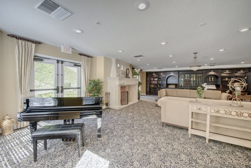 A spacious lobby area with a grand piano, sofas, and a fireplace.