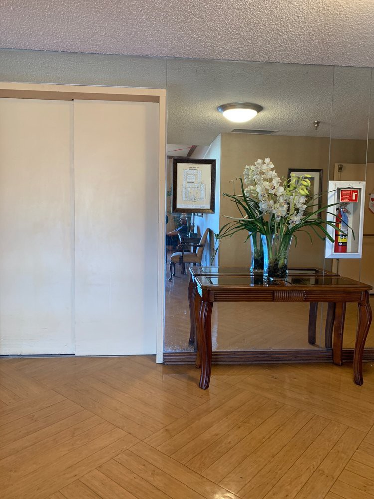 A lobby area featuring an elevator, a decorative table with flowers, and framed artwork on the wall.
