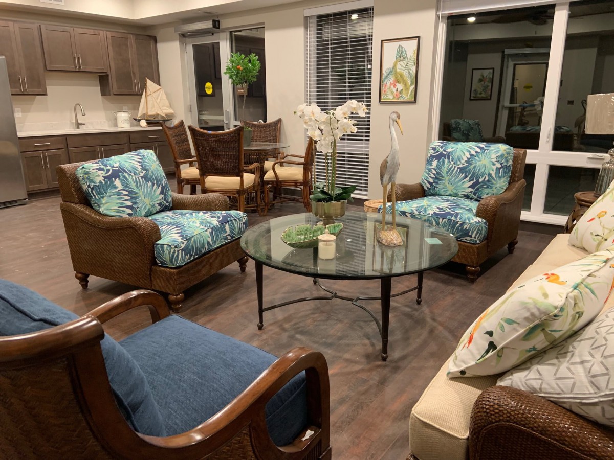 A cozy living room with a seating arrangement featuring colorful armchairs, a glass coffee table, and decorative plants.
