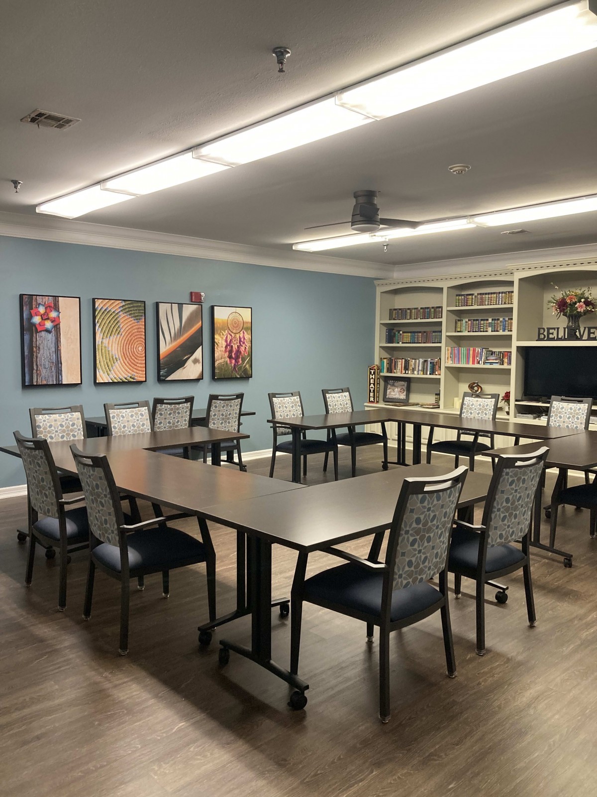 A well-organized conference room with tables, chairs, and bookshelves.
