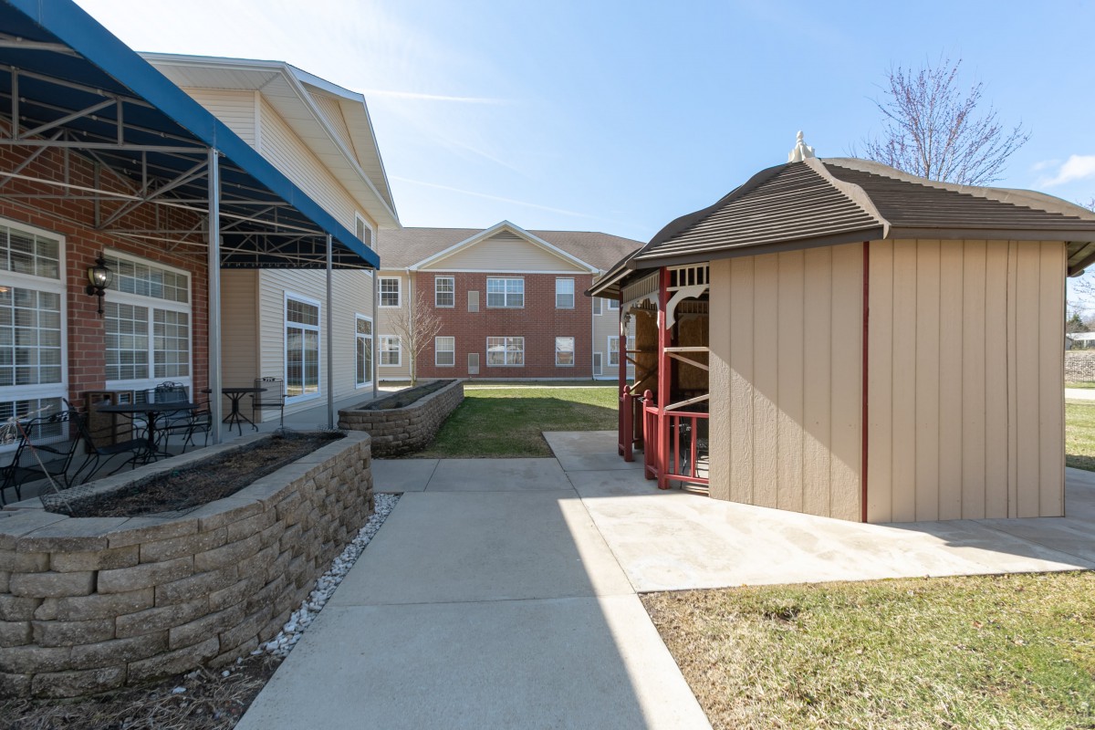 A sunny day view of a residential area with a pathway between two buildings and a gazebo.