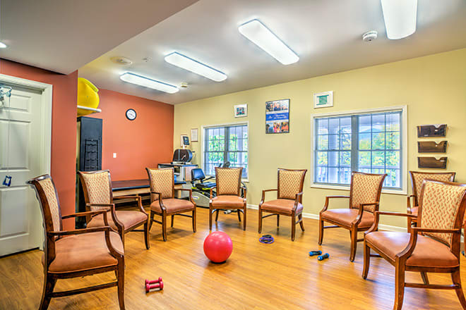 A therapy or meeting room with chairs arranged in a circle, featuring exercise equipment on the floor.