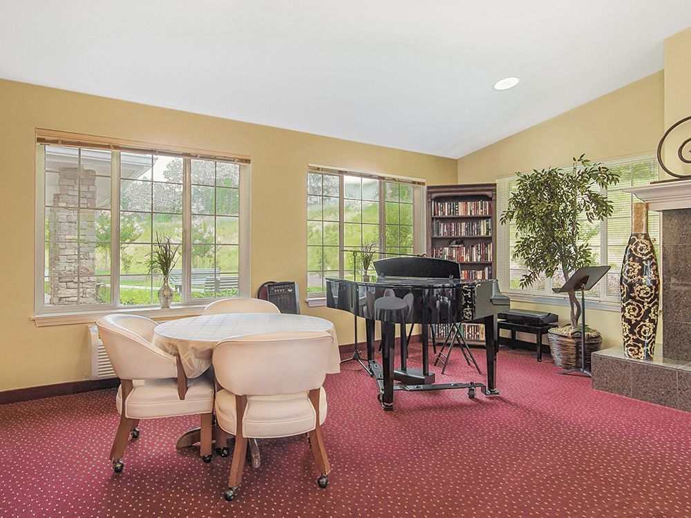 A cozy room with a grand piano, bookshelves, and comfortable seating.