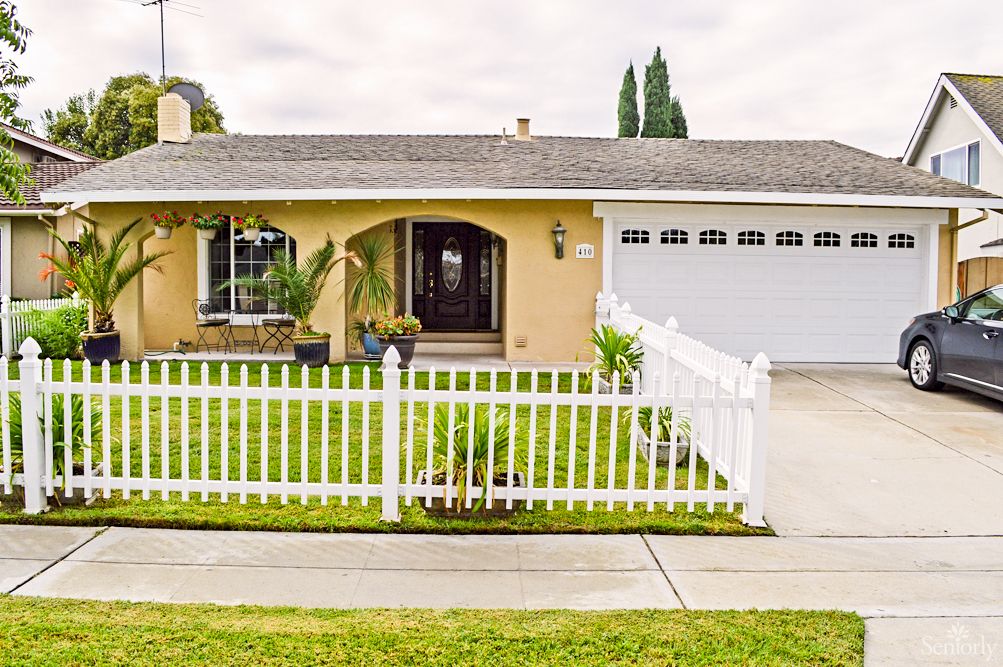 A cozy single-story house with a white picket fence and well-maintained front yard.
