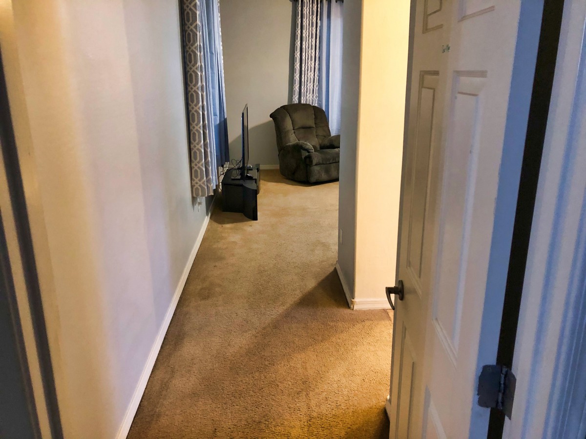 A cozy hallway with a carpeted floor and an armchair by the window.