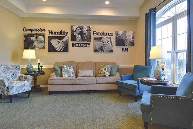 A cozy living room with a beige sofa, blue armchair, and wall art.