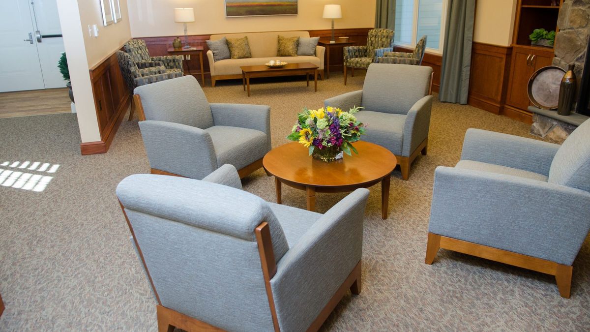 A cozy waiting room with comfortable chairs and a table adorned with a flower arrangement.