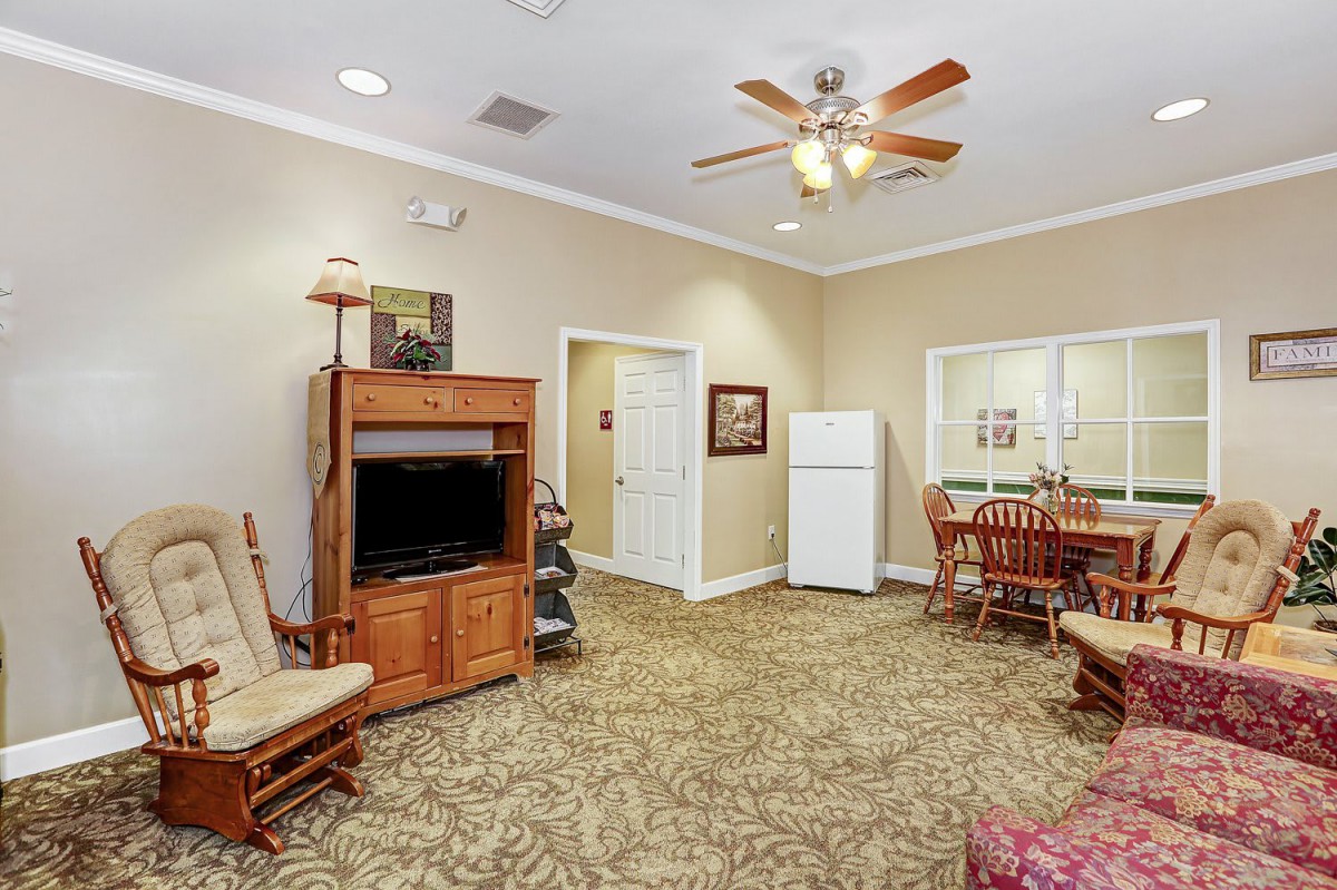 A cozy living room with a TV stand, ceiling fan, and dining area.