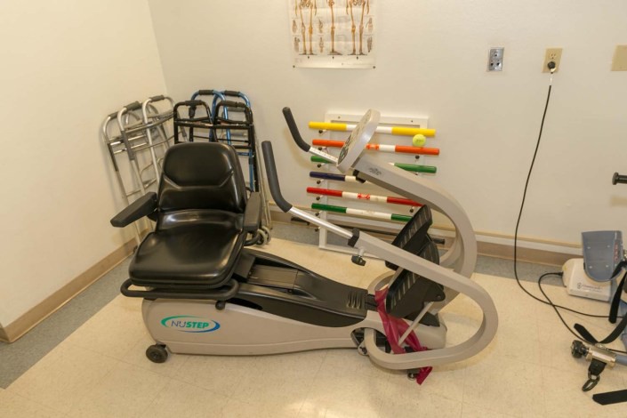 A stationary bike in a rehabilitation room with various fitness equipment.