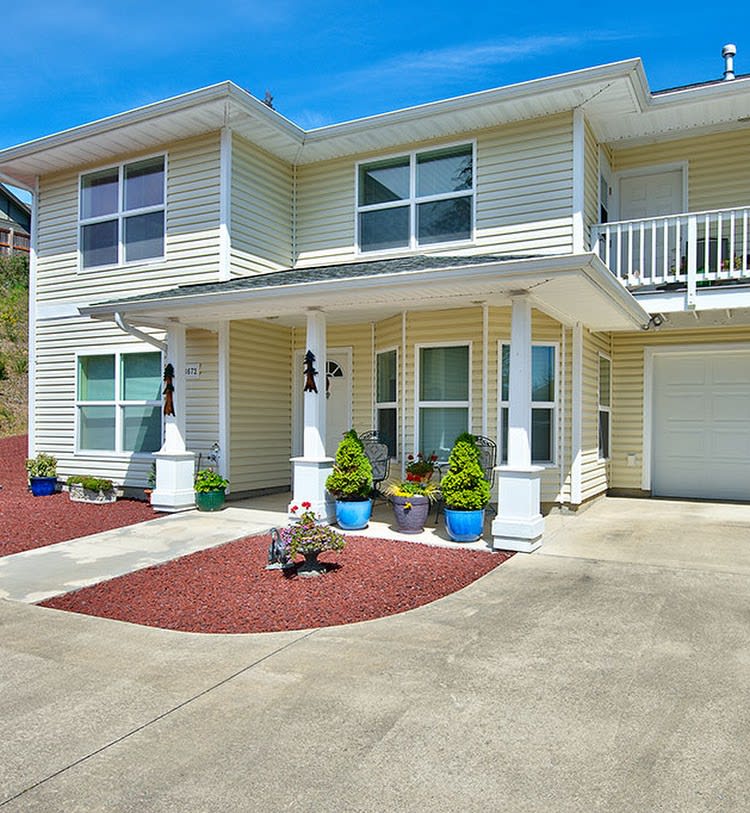 A two-story residential house with a porch, balcony, and driveway.