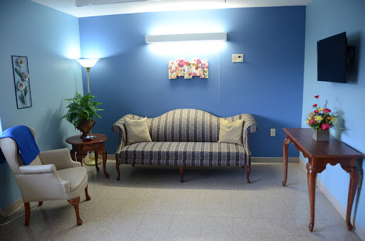 A cozy living room setup featuring a striped sofa, a small table, and a potted plant against a blue wall.