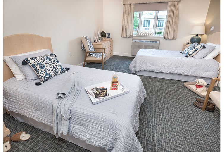 A cozy hotel room with two neatly made beds, a tray with food, and a window providing natural light.