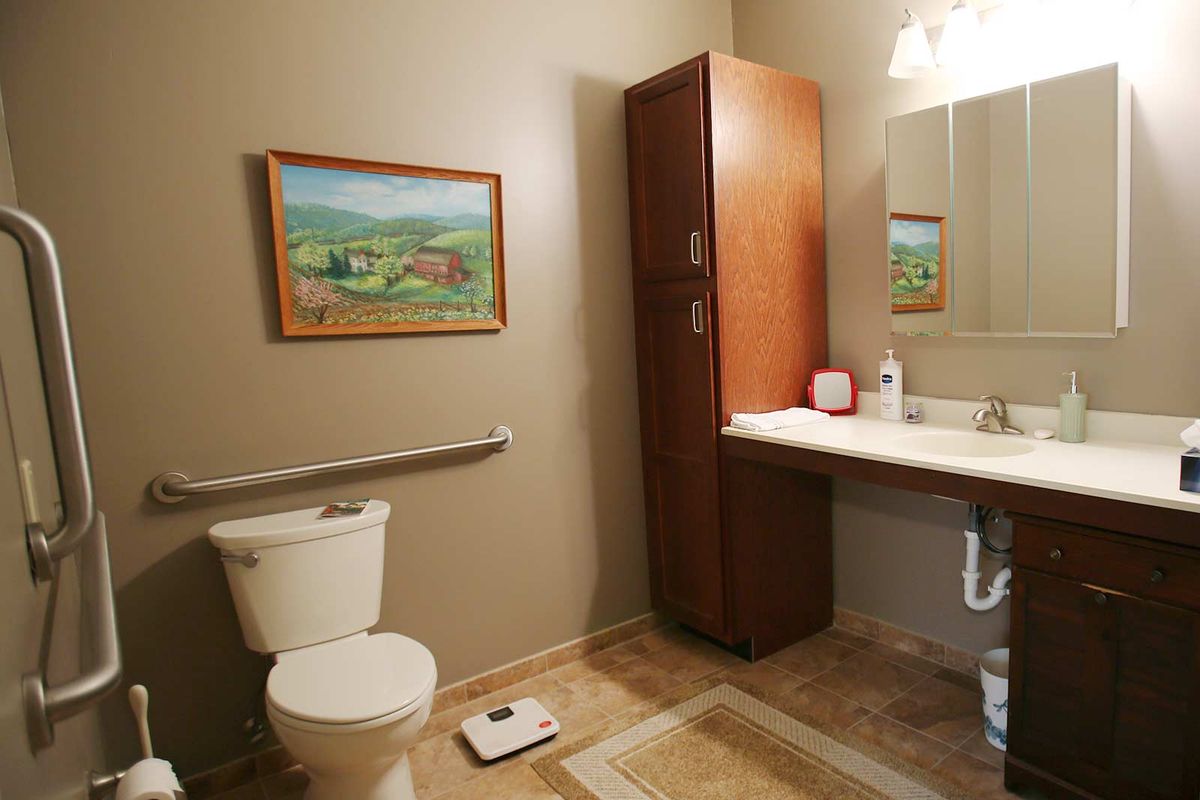 A well-organized bathroom with a toilet, sink, cabinet, and decorative painting on the wall.