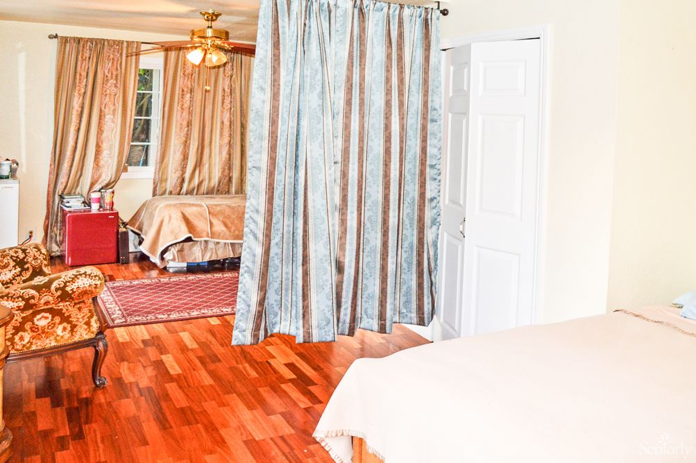 A cozy bedroom with hardwood flooring and curtains separating the space.