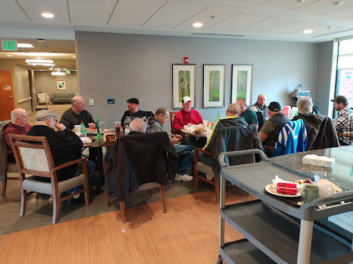 A group of people gathered around a table for a discussion in a cozy indoor setting.