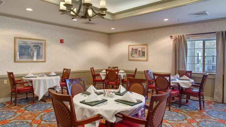A cozy restaurant dining area with neatly arranged tables and chairs, featuring elegant table settings.