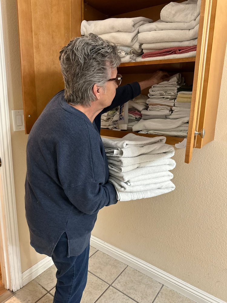 A person is organizing towels in a cupboard.