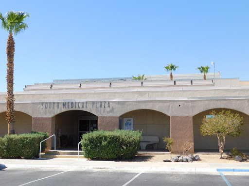 A modern commercial building with palm trees under a clear blue sky.