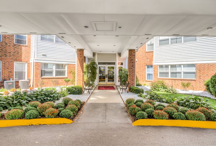 A well-maintained building entrance with landscaping and a paved walkway.