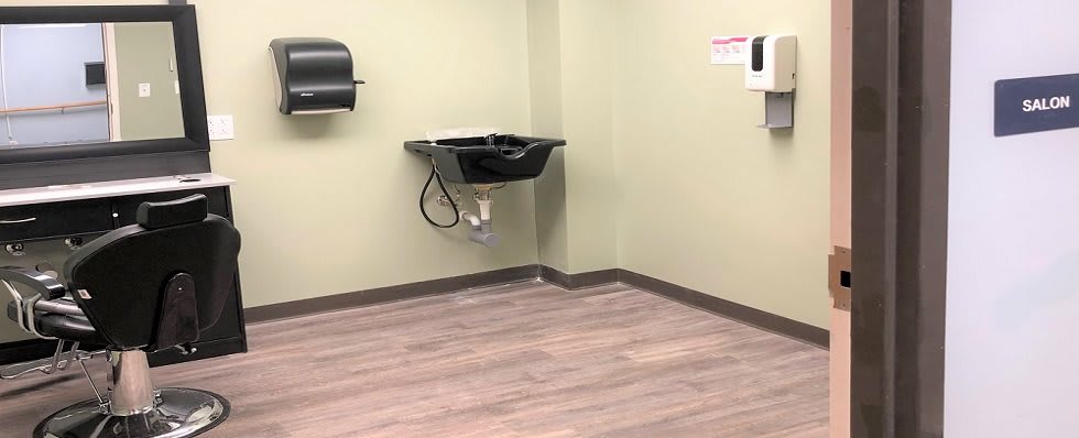 An empty room with a wall-mounted sink and wooden flooring.