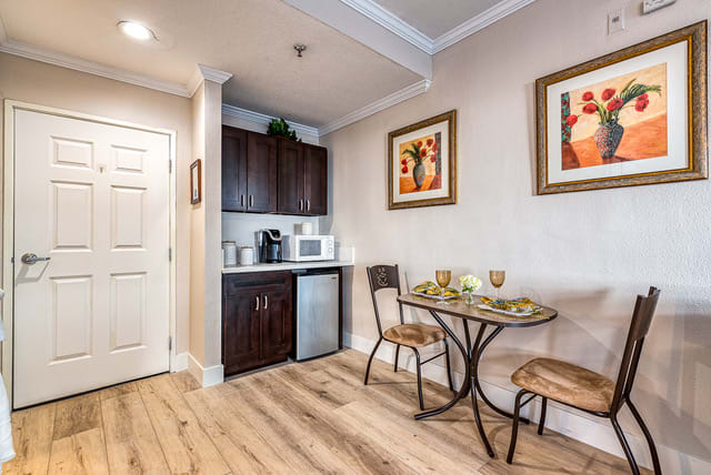 A cozy kitchenette with a small dining area, featuring a microwave, mini fridge, and wall artwork.