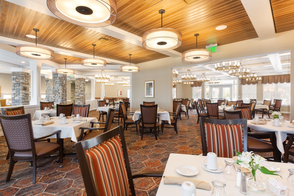 A modern restaurant dining area with neatly arranged tables and stylish lighting fixtures.